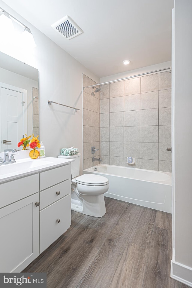 full bathroom featuring hardwood / wood-style floors, vanity, toilet, and tiled shower / bath