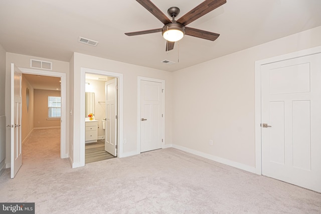 unfurnished bedroom featuring light carpet, connected bathroom, and ceiling fan