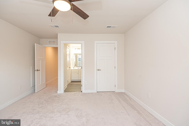 unfurnished bedroom featuring ensuite bathroom, ceiling fan, and light colored carpet