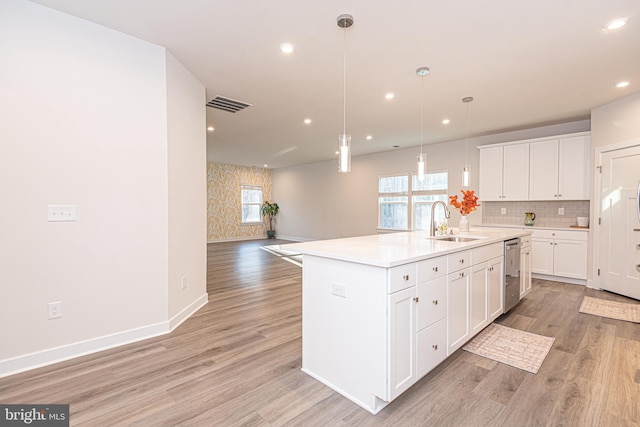 kitchen with sink, stainless steel dishwasher, light wood-type flooring, an island with sink, and white cabinetry