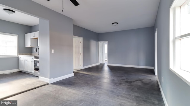 unfurnished living room featuring ceiling fan, dark wood-type flooring, and sink