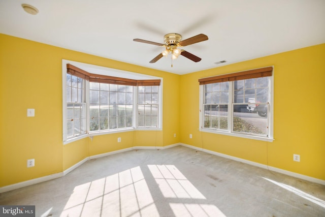 carpeted spare room featuring ceiling fan and a healthy amount of sunlight