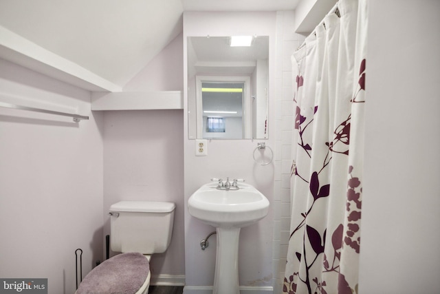 bathroom featuring a shower with curtain, lofted ceiling, and toilet