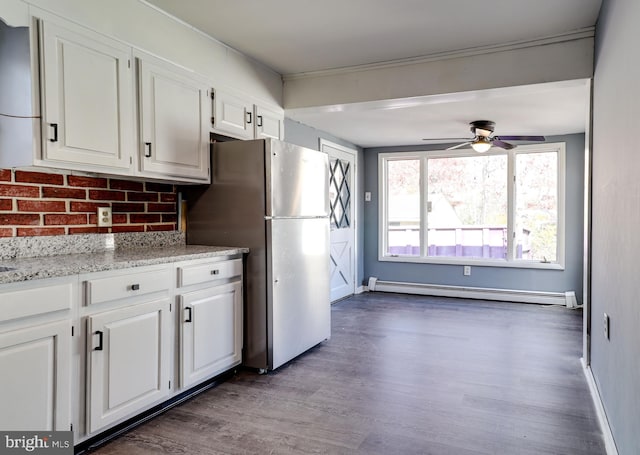 kitchen with dark wood-type flooring, stainless steel fridge, baseboard heating, white cabinetry, and light stone countertops