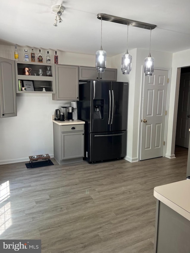 kitchen with refrigerator with ice dispenser, gray cabinets, wood-type flooring, and pendant lighting