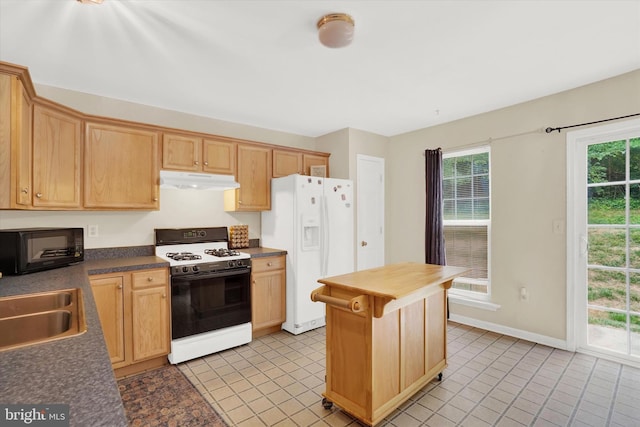 kitchen featuring light brown cabinetry, sink, light tile patterned floors, and white appliances