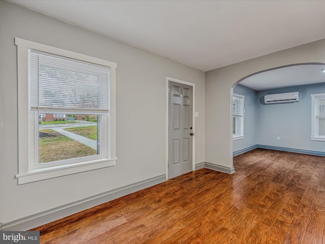 spare room featuring hardwood / wood-style floors and a wall unit AC