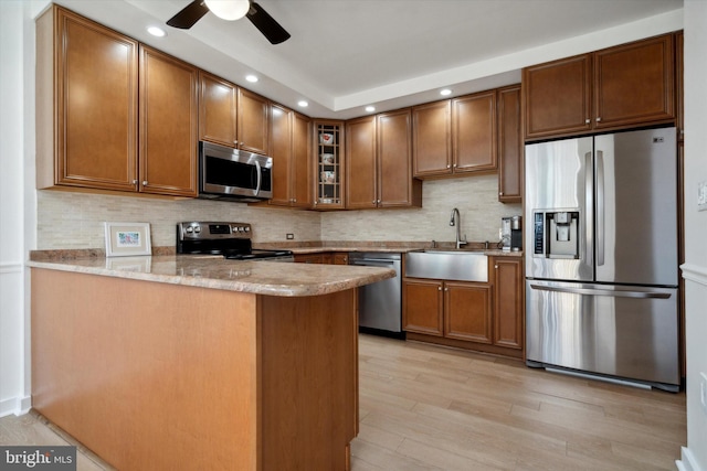 kitchen featuring kitchen peninsula, sink, stainless steel appliances, and light hardwood / wood-style floors