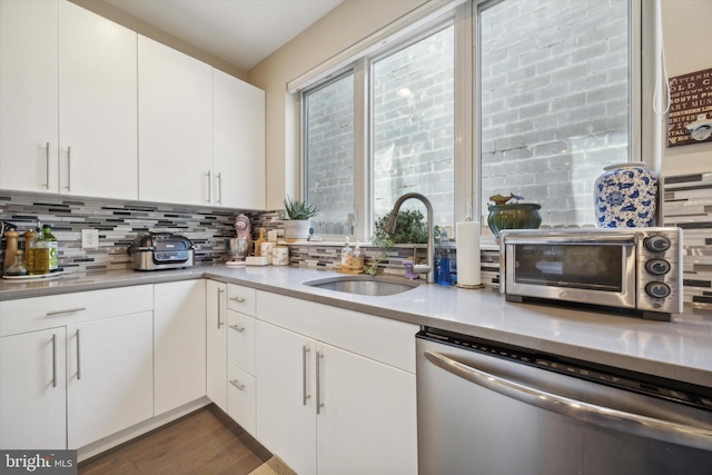 kitchen with backsplash, white cabinets, sink, stainless steel dishwasher, and dark hardwood / wood-style flooring