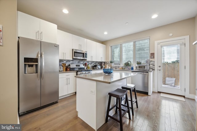 kitchen featuring a kitchen island, white cabinetry, stainless steel appliances, and a breakfast bar area