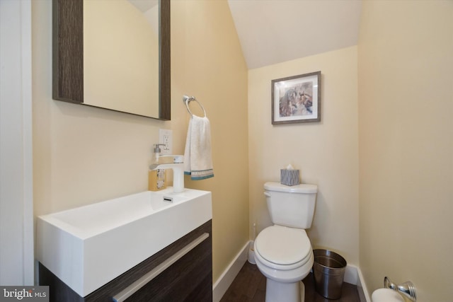 bathroom with vanity, hardwood / wood-style flooring, toilet, and lofted ceiling