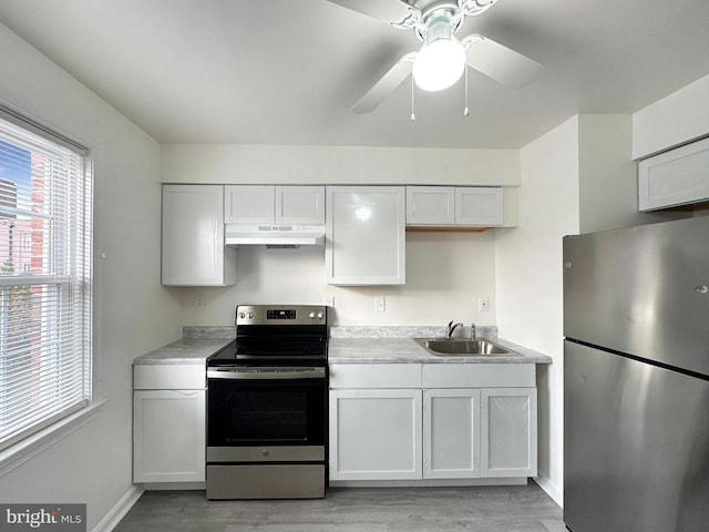 kitchen with white cabinets, sink, stainless steel appliances, and light hardwood / wood-style flooring