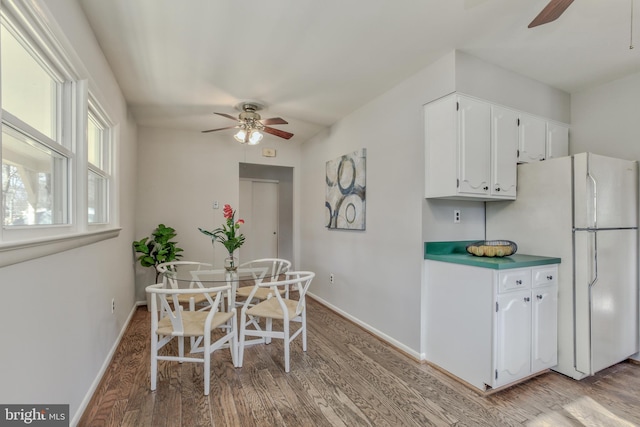 dining room with light wood-style floors, ceiling fan, and baseboards