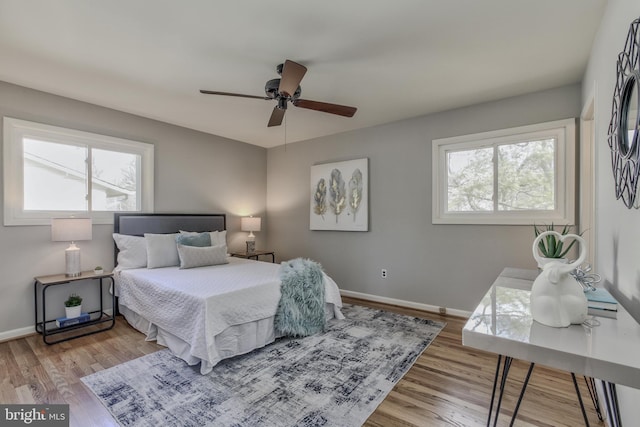 bedroom with a ceiling fan, baseboards, and wood finished floors