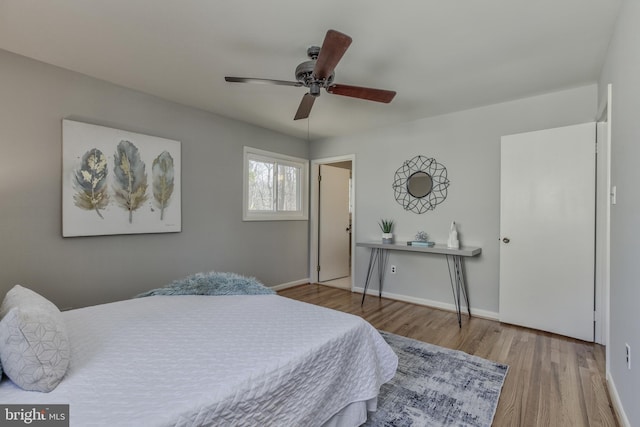 bedroom featuring a ceiling fan, baseboards, and wood finished floors