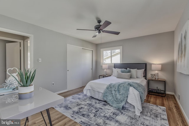 bedroom featuring ceiling fan, a closet, wood finished floors, and baseboards