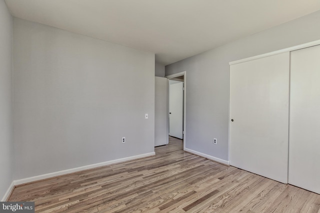 unfurnished bedroom with a closet, wood finished floors, and baseboards