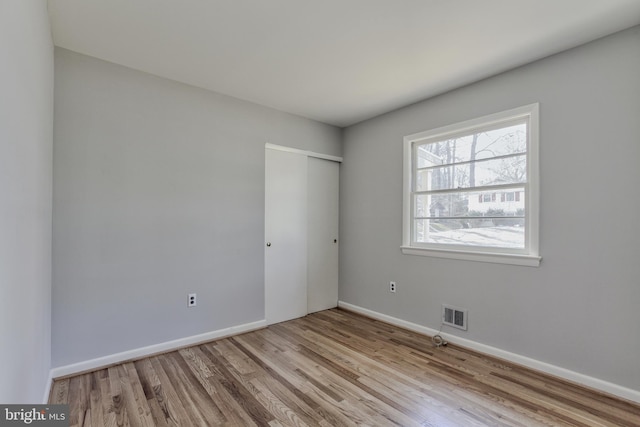 empty room featuring visible vents, baseboards, and wood finished floors