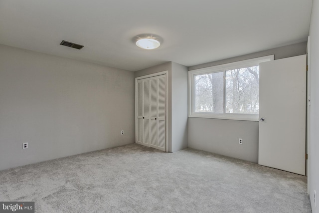 unfurnished bedroom with carpet floors, a closet, and visible vents