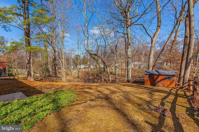 view of yard featuring a storage shed, fence, and an outbuilding