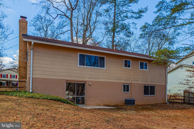 view of home's exterior with a chimney, fence, a yard, central AC, and stucco siding