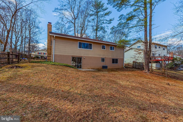 rear view of house featuring a fenced backyard, a chimney, cooling unit, and a yard