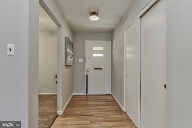 doorway featuring light wood finished floors and baseboards