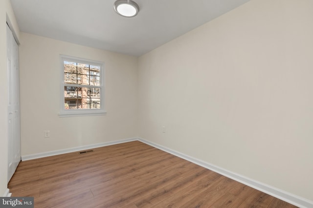 spare room featuring visible vents, baseboards, and wood finished floors