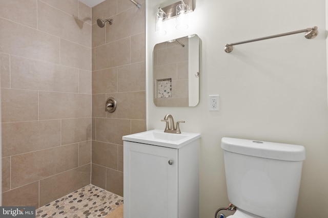 bathroom with toilet, vanity, and a tile shower