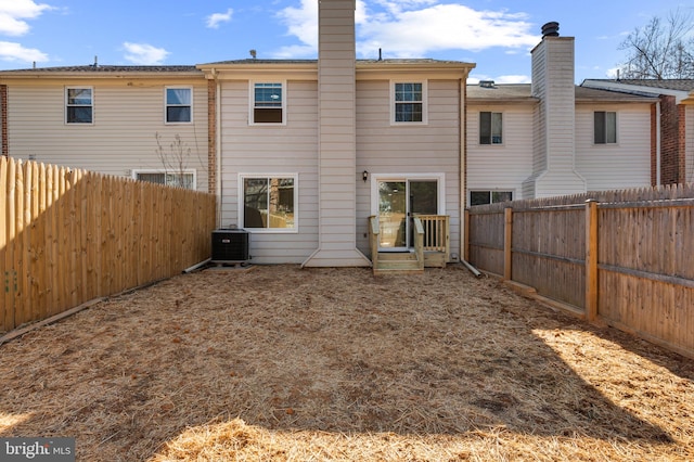 back of house featuring a fenced backyard, central AC, and a chimney