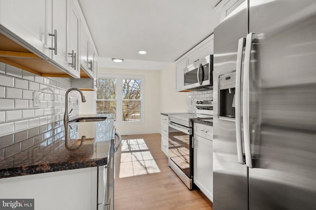 kitchen featuring light wood-style flooring, appliances with stainless steel finishes, white cabinetry, and a sink