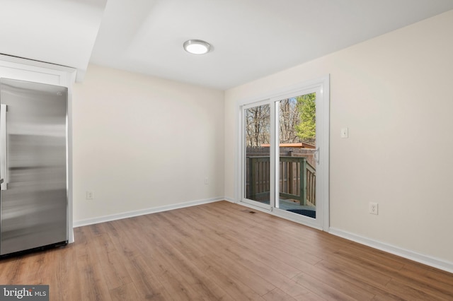 spare room featuring visible vents, baseboards, and wood finished floors