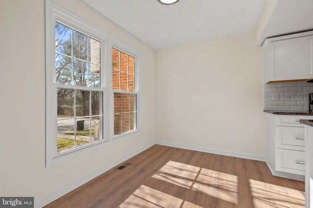 unfurnished dining area with visible vents, baseboards, and wood finished floors