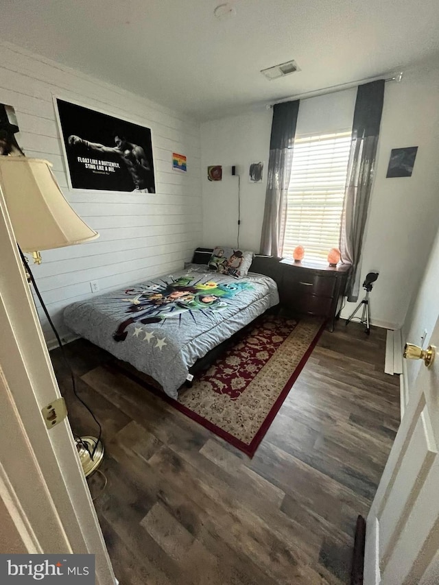 bedroom featuring dark hardwood / wood-style flooring and wood walls