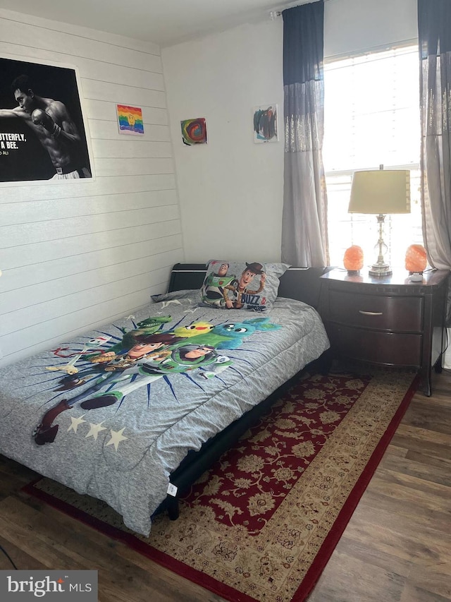 bedroom with wood-type flooring and wooden walls