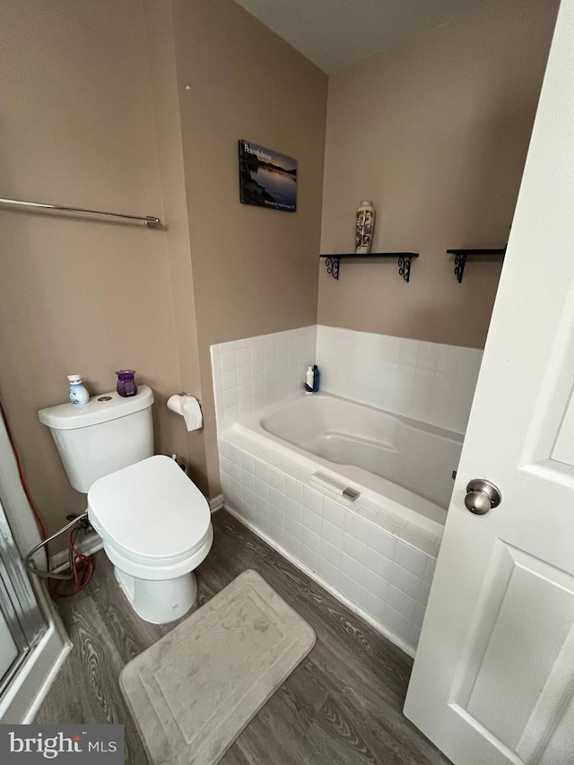 bathroom featuring toilet, wood-type flooring, and tiled tub