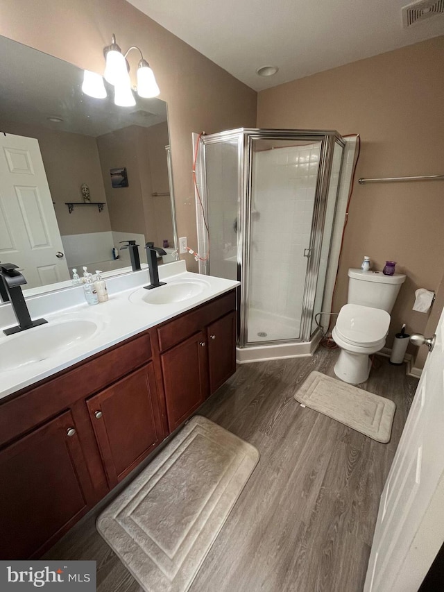 bathroom with hardwood / wood-style floors, vanity, toilet, and walk in shower