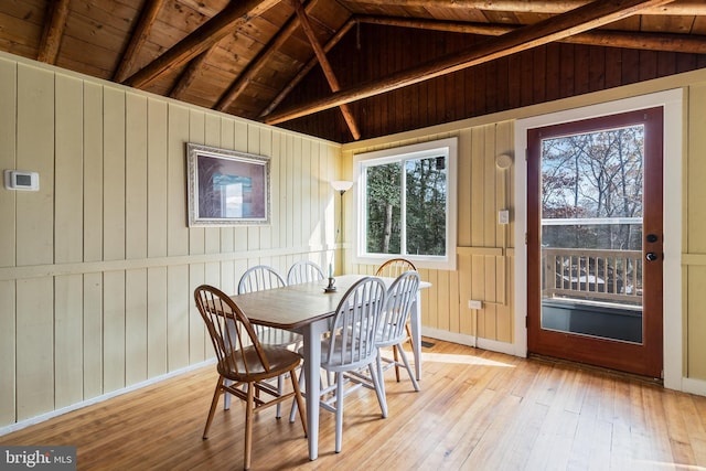 dining area featuring vaulted ceiling with beams, wood walls, and wood ceiling