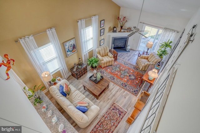 living room featuring wood-type flooring, high vaulted ceiling, and ceiling fan