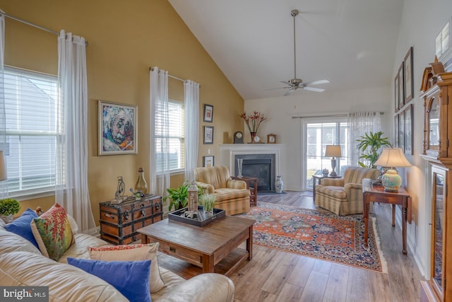 living room with light hardwood / wood-style floors, high vaulted ceiling, plenty of natural light, and ceiling fan