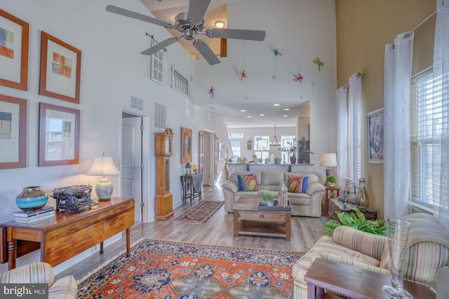 living room featuring ceiling fan, light hardwood / wood-style floors, and a high ceiling