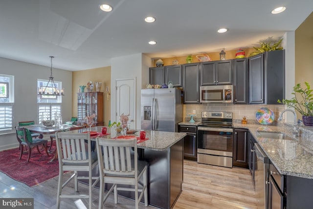 kitchen featuring a center island, sink, appliances with stainless steel finishes, decorative light fixtures, and a chandelier