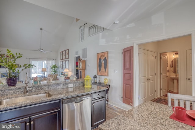 kitchen featuring light stone countertops, stainless steel dishwasher, ceiling fan, sink, and lofted ceiling