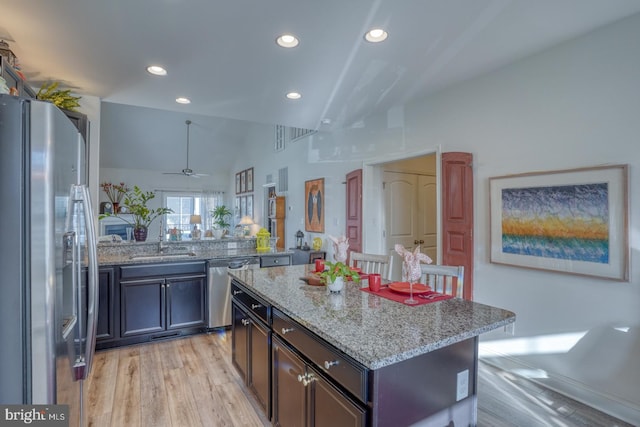 kitchen with stainless steel appliances, ceiling fan, sink, a kitchen island, and lofted ceiling