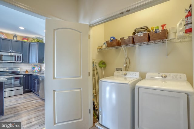 clothes washing area featuring washing machine and dryer and light hardwood / wood-style flooring