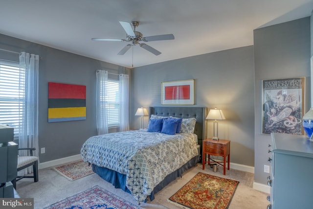 bedroom featuring ceiling fan, light colored carpet, and multiple windows