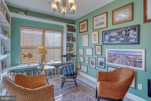 living area featuring built in shelves, light colored carpet, and a chandelier