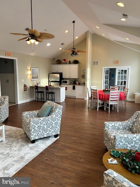 living room featuring a towering ceiling, dark hardwood / wood-style floors, and ceiling fan