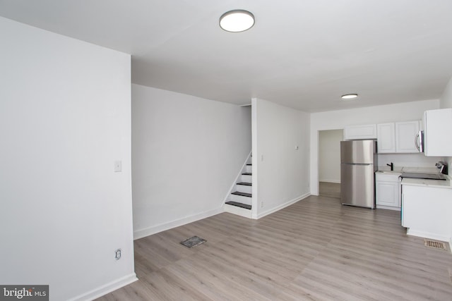 interior space featuring white cabinets, stainless steel appliances, and light hardwood / wood-style flooring