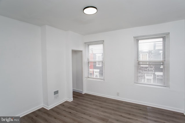 empty room featuring dark wood-type flooring and a healthy amount of sunlight